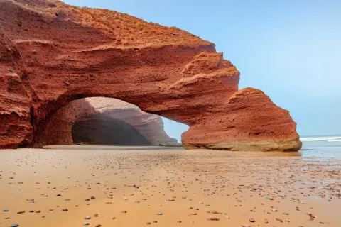 Piękne marokańskie plaże z czerwoną skalną bramą i kamienistym brzegiem.