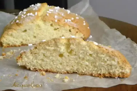 Fetta di ciambella romagnola soffice e dorata, cosparsa di zuccherini, su carta da forno.