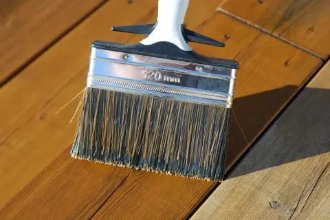 Pensel applicerar olja på altanen. Perfekt temperatur för att olja altanen.