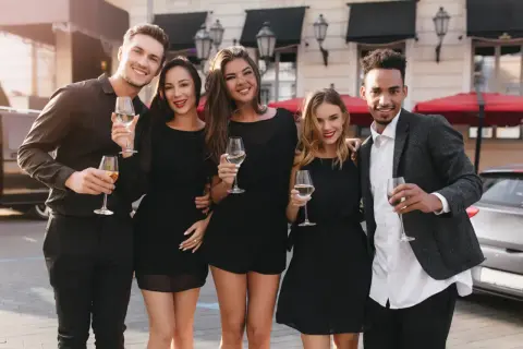 Fünf Freunde in eleganter Cocktailgarderobe stoßen mit Champagner an.