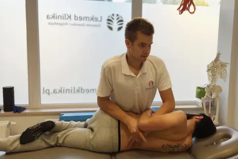Fizjoterapeuta wykonuje terapię manualną, pomagając pacjentowi po nastawieniu kręgosłupa.