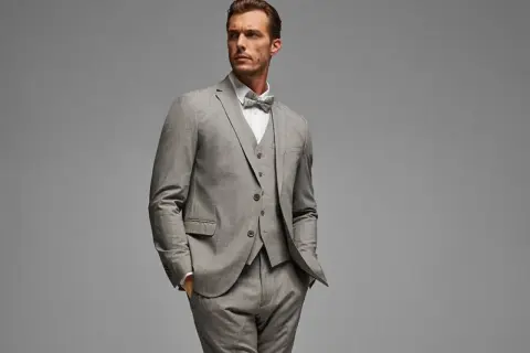 Ein Mann im eleganten grauen Anzug mit Weste und Fliege. So gelingt das Anzug reinigen ohne waschen.