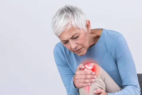 Frau mit Arthrose-Schmerzen im Knie, die sich fragt, welche Vitamine bei Arthrose helfen könnten.