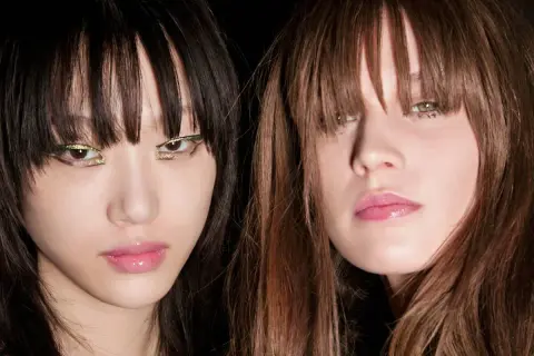 Dos modelos con flequillo hacia adelante y maquillaje llamativo en los ojos.