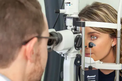 Un ophtalmologue examine l'œil d'une patiente avec un biomicroscope.