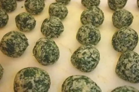 Spinat-Ricotta-Nocken auf weißem Untergrund.