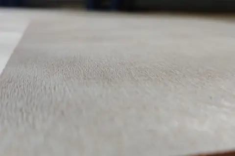 Textura de madera de okume arbol, con vetas finas y claras, mostrando la belleza natural del material.