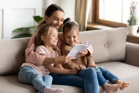 Mama czyta swoim córeczkom krótkie wierszyki dla bff. Radość i bliskość na kanapie.