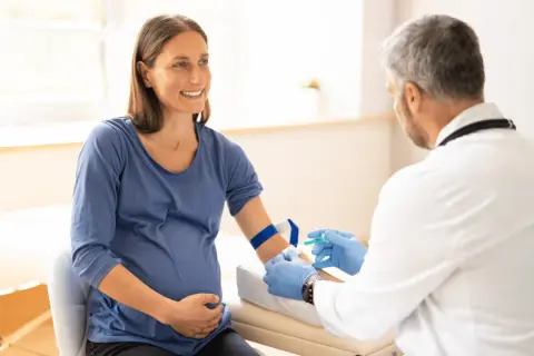 Lekarz pobiera krew od ciężarnej kobiety, aby wykluczyć konflikt serologiczny.