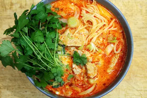 Miseczka zupy curry z makaronem, mięsem i świeżą kolendrą.