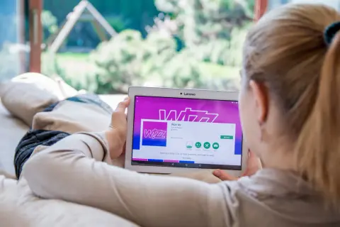Kobieta przegląda w aplikacji Wizz Air na tablecie, planując tani lot.
