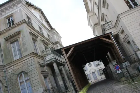 Passage couvert menant au palais du roi de Rome, avec des bâtiments anciens et une cour pavée.
