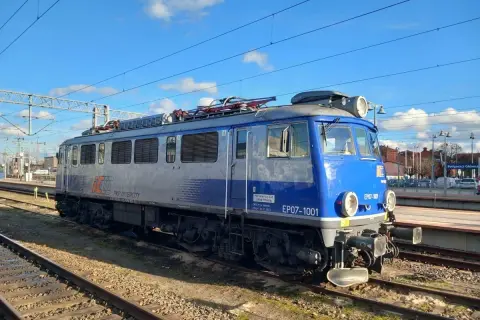 Niebiesko-szara lokomotywa PKP Intercity EP07-1001 na torach kolejowych.