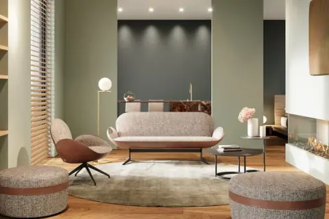 Modernes Wohnzimmer mit einem stilvollen Sofa als Raumteiler. Ein Sessel, Hocker und ein Kamin schaffen Gemütlichkeit.