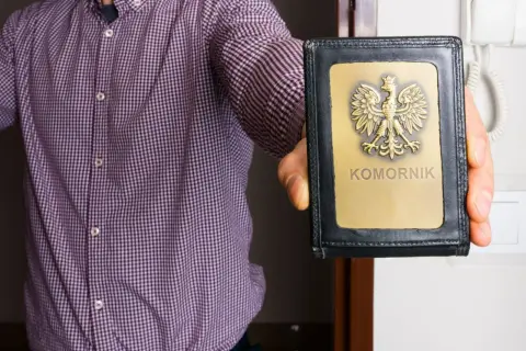 Mężczyzna w koszuli pokazuje legitymację z napisem "KOMORNIK". Czy komornik może zabrać świadczenie urlopowe?