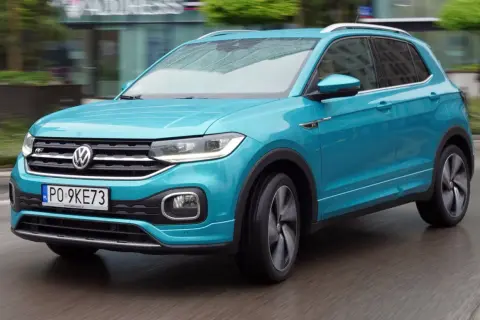 Turkusowy Volkswagen T-Cross w ruchu miejskim, z widocznym numerem rejestracyjnym PO 9KE73.