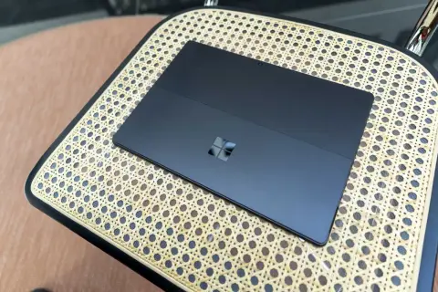 Ciemny tablet z logo Windows na plecach, działający na Windows 11 ARM, leży na plecionej powierzchni.