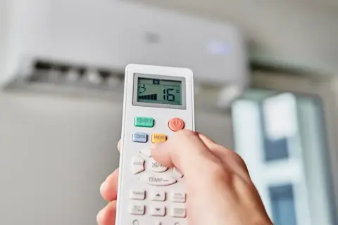 Main tenant effectue le réglage clim télécommande pour une température de 16°C.