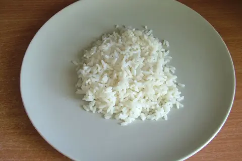 Ugotowany ryż na jasnoszarym talerzu.