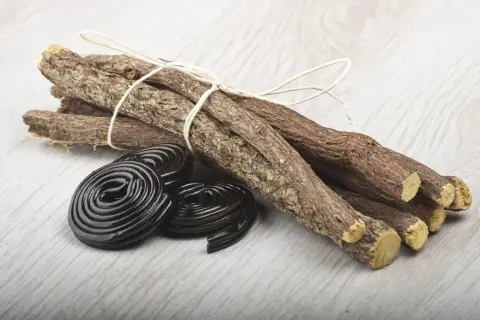 Korzenie lukrecji związane sznurkiem i czarne, spiralne cukierki. Idealne do przygotowania naparu z lukrecji.