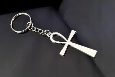 Srebrny brelok z symbolem ankh, starożytnym egipskim znakiem życia, na czarnym tle.
