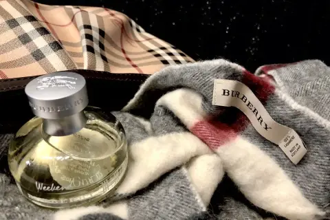 Flakon perfum Burberry Weekend obok szarego szala z charakterystyczną kratą. Idealny zestaw na weekend.