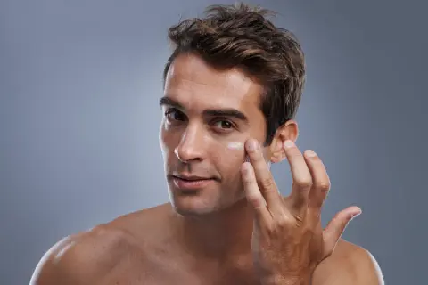 Hombre aplicándose crema en el rostro. El cuidado facial del hombre es esencial para una piel sana y radiante.