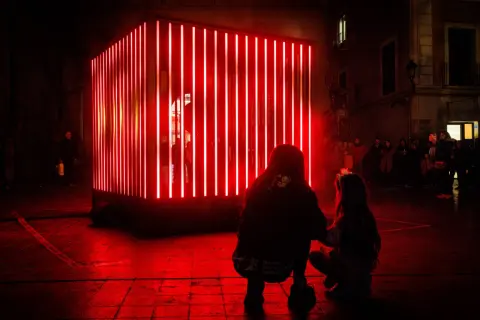 Dos personas observan una instalación de luces rojas en Zaragoza, un adelanto de lo que Zaragoza luce 2026.