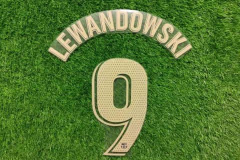 Numer 9 z nazwiskiem Lewandowski i logo Barcy na zielonej murawie.