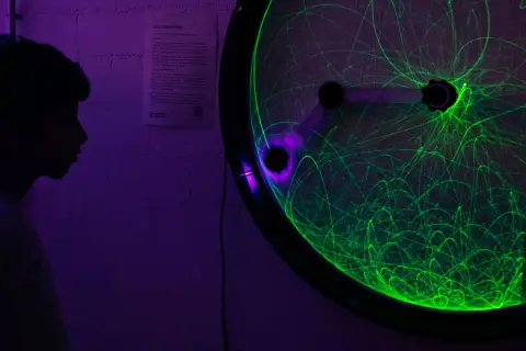 Ein Junge bestaunt ein Doppelpendel mit grünen Lichtspuren bei der Nacht der Wissenschaft Berlin.