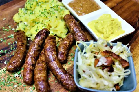 Herzhafte Rehbratwurst mit Kartoffelpüree, Krautsalat und Senf. Ein tolles rehbratwurst rezept für Genießer.