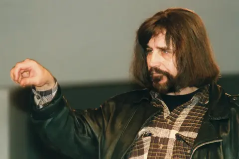 Czesław Niemen, jakby śpiewał "Sen o Warszawie tekst", z zaciśniętą pięścią i charakterystyczną fryzurą.