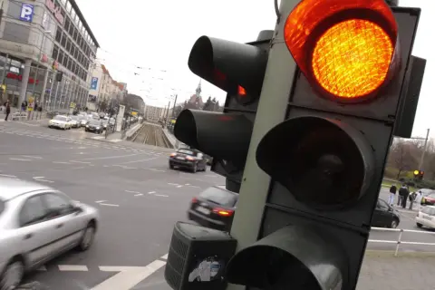 Pomarańczowe światło na sygnalizatorze drogowym. Ruch uliczny w mieście, samochody czekają na zmianę świateł.