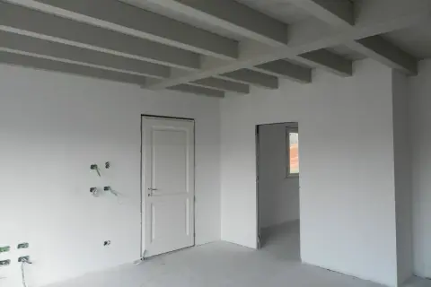 Interno in fase di finitura: pareti bianche, travi a vista e predisposizioni elettriche. Lo spessore intonaco interno è uniforme.