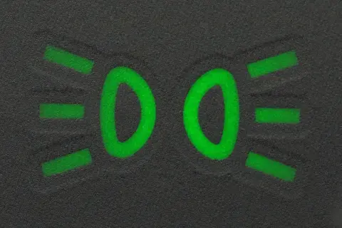 Zielony symbol świateł mijania na ciemnym tle.