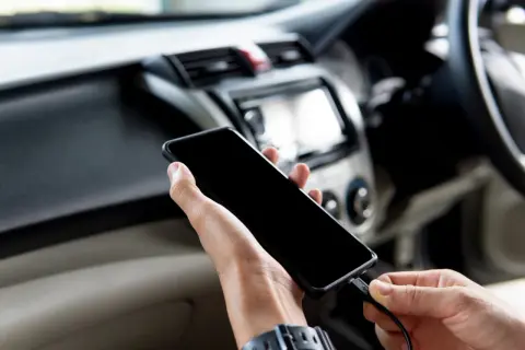 Ręce podłączają telefon do radia samochodowego, aby dołożenie bluetooth do radia samochodowego było proste.