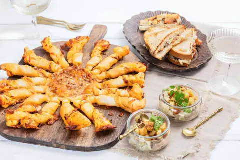 Un apéro réussi : tarte feuilletée en forme de soleil, mini sandwichs, verrines et coupes de champagne. Idéal pour savoir quoi apporter pour une invitation à un apéro.