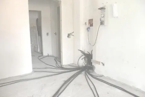 Rifacimento impianto elettrico in corso. Cavi neri si diramano dal muro, pronti per la manutenzione ordinaria o straordinaria.