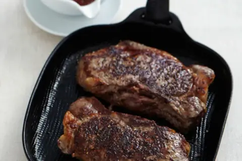 Zwei saftige Rumpsteaks braten in einer Grillpfanne, perfekt gewürzt und mit einer köstlichen Kruste.