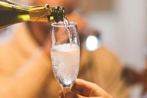 Ein Glas wird mit sprudelndem Cremant gefüllt. Was ist ein Cremant? Ein feiner Schaumwein, perfekt für besondere Anlässe.