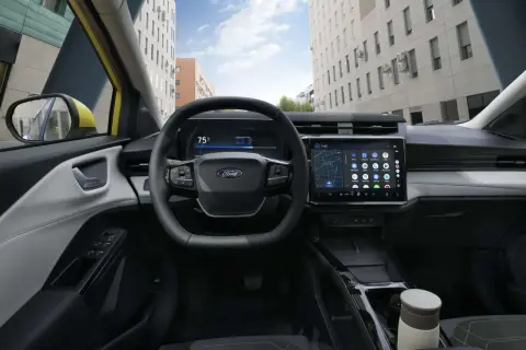 Vue du **ford puma interieur** moderne avec écran tactile, volant multifonction et tableau de bord numérique. La ville s'affiche à travers le pare-brise.