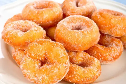 Montón de rosquillas caseras de toda la vida, doradas y espolvoreadas con azúcar.