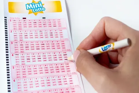 Ręka zaznacza liczby na kuponie Mini Lotto. Zastanawiasz się, ile lotto płaci za trójkę?