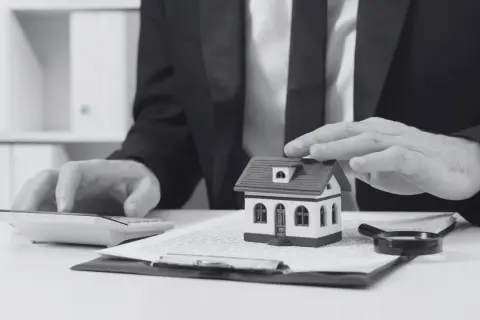 Biznesmen z lupą i kalkulatorem analizuje dokumenty, by zapobiec przerwaniu biegu zasiedzenia nieruchomości.