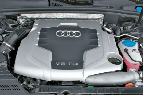 Silnik V6 TDI Audi z widocznym logo i oznaczeniem pojemności. Pod maską widać elementy układu dolotowego i płyny eksploatacyjne.