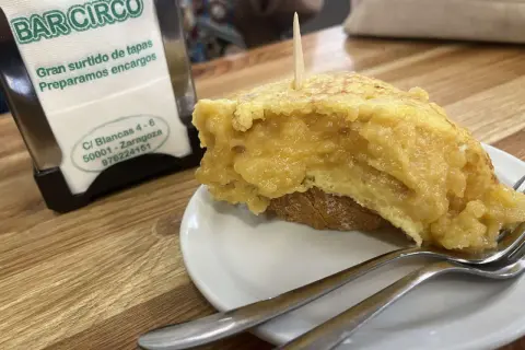 Deliciosa tortilla de patata zaragozana en Bar Circo, lista para disfrutar con tenedores.