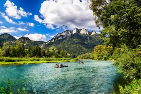 Flöße auf einem türkisfarbenen Fluss vor bewaldeten Bergen. Ein idyllisches Bild für Ausflugsziele Polen.