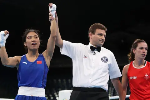 A boxer in a blue uniform with the Chinese flag raises her arm in victory as a referee holds it up. The question of what weight class is 150 in boxing is on many minds.