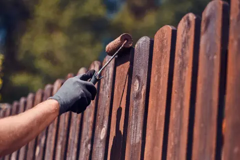 Aplicando protector a la valla de madera para saber como tratar la madera para que no se pudra.