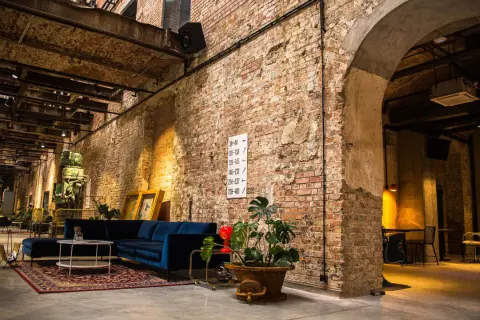 Wnętrze hotelu Cukrownia Żnin: industrialny klimat, ceglane ściany, wygodna granatowa sofa i zabytkowa maszyna.
